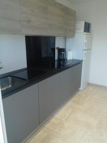 une cuisine avec des armoires blanches et un comptoir noir dans l'établissement Appartement cannes, au Cannet