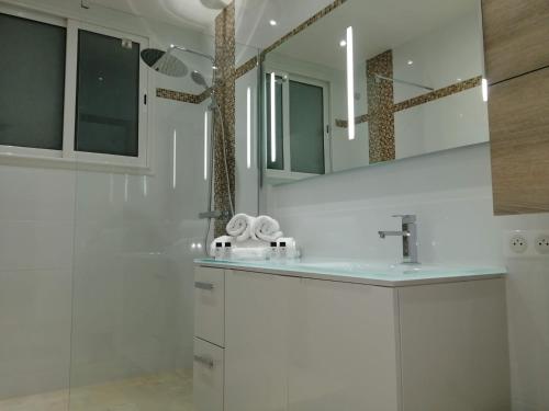 une salle de bain blanche avec un lavabo et un miroir dans l'établissement Appartement cannes, au Cannet
