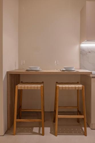 a wooden table with two plates on top and two stools at Earthy Haven-Minimalist Luxury Studio & Hot Tub in Rhodes Town