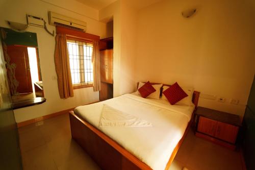 a bedroom with a bed with white sheets and red pillows at Ramana Towers in Tiruvannāmalai