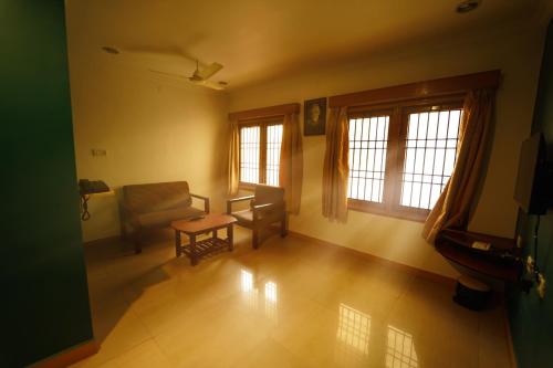 an empty living room with a chair and windows at Ramana Towers in Tiruvannāmalai