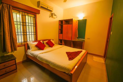 a bedroom with a bed with red pillows on it at Ramana Towers in Tiruvannāmalai