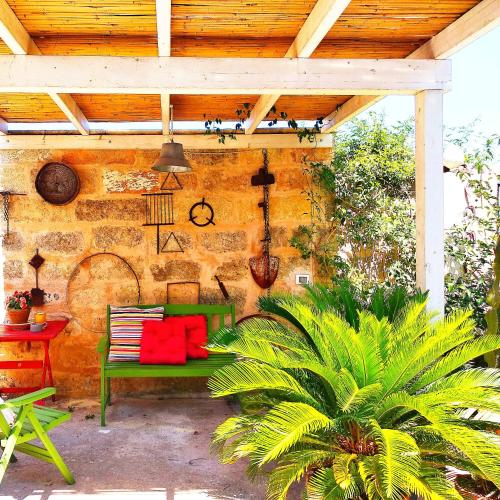 a patio with a green bench with red pillows at Masseria delle Rose 1760 in Alessano