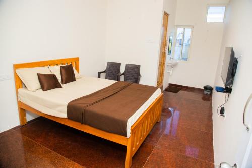 a bedroom with a bed and two chairs and a television at Orange Residency in Tirupporūr
