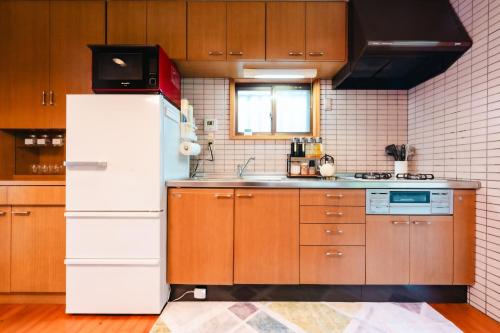 a kitchen with a white refrigerator and a sink at Kurokawa Mori No Kiki in Minamioguni