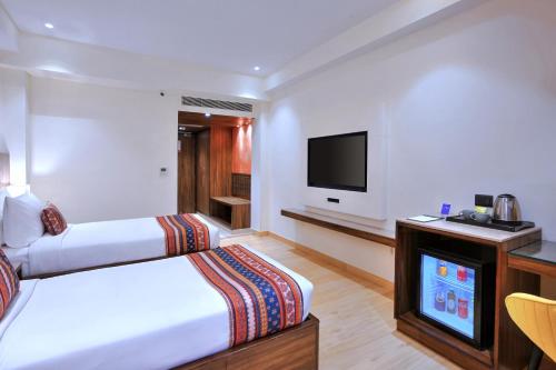 a hotel room with a bed and a flat screen tv at Golden Tulip Agra in Agra