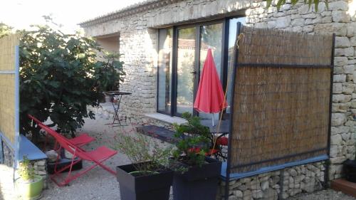 un patio con ombrellone rosso e alcune piante di La cigale bleue a Gordes