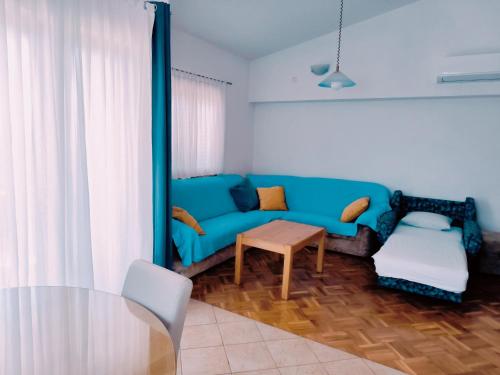 a living room with a blue couch and a table at Apartments Jurjevic in Petrcane