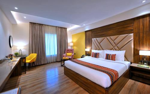 アグラにあるGolden Tulip Agraの大きなベッドと机があるホテルの部屋