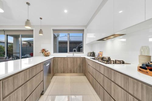 a large kitchen with white countertops and wooden cabinets at Luxury on City Fringe in Klemzig By Elegant Stays in Campbelltown