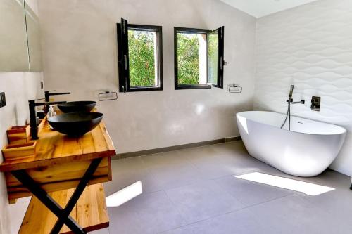 La salle de bains est pourvue d'une grande baignoire blanche et d'un lavabo. dans l'établissement Villa Domitia Splendid View 5mn walk from center of Saint Remy, à Saint-Rémy-de-Provence