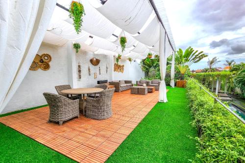an outdoor patio with a table and chairs and grass at Da Vinci The Villa by Nagisa Bali in Tumbak Bayuh