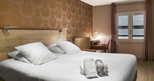 a bedroom with a white bed with towels on it at Grand Hôtel Dauphiné Toulon, Boutique Hôtel & Suites in Toulon