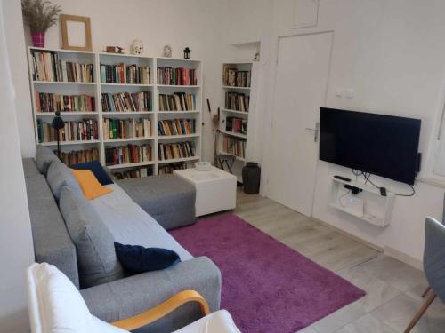 a living room with a couch and a tv and book shelves at Beautiful apartment with 2 terraces and a parking space in Kaštela