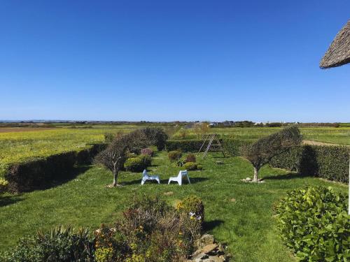 a garden with a table and chairs in the grass at Longère - 10 personnes - Vue mer in Tréguennec