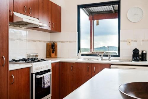 a kitchen with wooden cabinets and a stove and a window at Karrak Reach Forest Retreat in Denmark