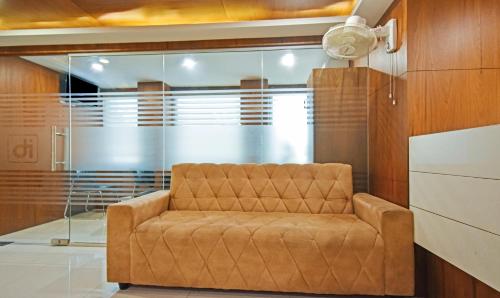 a brown couch in a room with glass walls at Itsy Hotels Deluxe Inn in Chennai