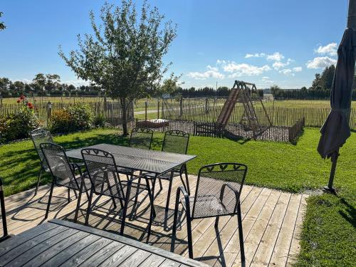 a table and chairs on a deck with a playground at Ferienwohnung auf dem Alpaka-Hof in Rubkow