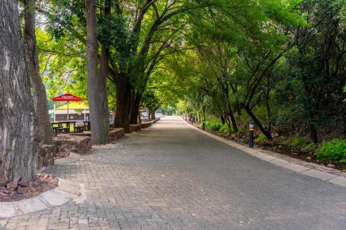 a cobblestone road with trees and a table and benches at ATKV Klein-Kariba in Bela-Bela