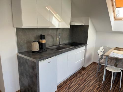 a kitchen with white cabinets and a sink and a table at Willa Sarbinowo in Sarbinowo