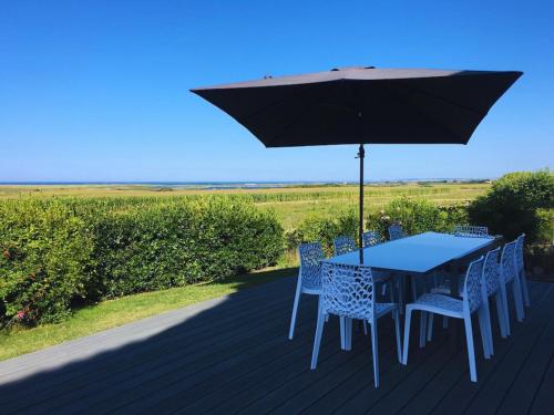 a table and chairs under an umbrella on a deck at Longère - 10 personnes - Vue mer in Tréguennec