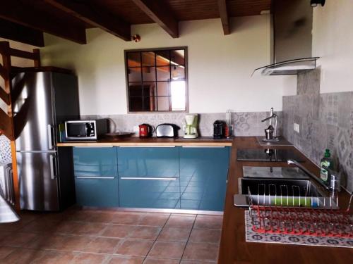 a kitchen with blue cabinets and a stainless steel refrigerator at Longère - 10 personnes - Vue mer in Tréguennec