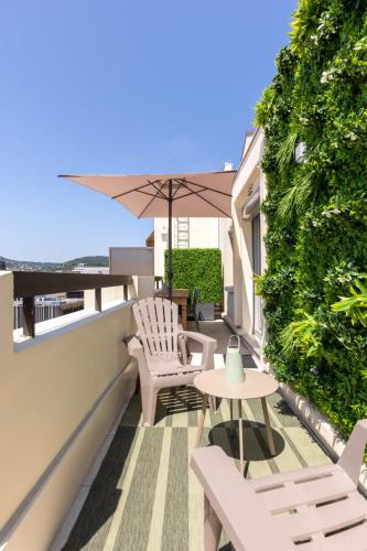 a balcony with chairs and a table and an umbrella at At home in Clermont, Place de Jaude in Clermont-Ferrand