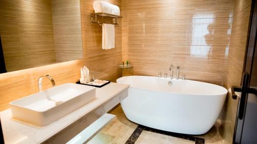 a bathroom with a large white tub and a sink at ST Hotel Wattay Airport in Vientiane
