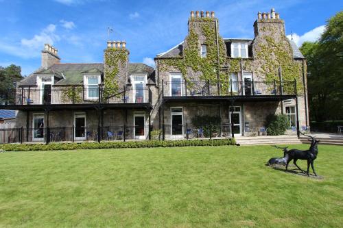 a dog standing in front of a large house at Loch Kinord Hotel in Dinnet
