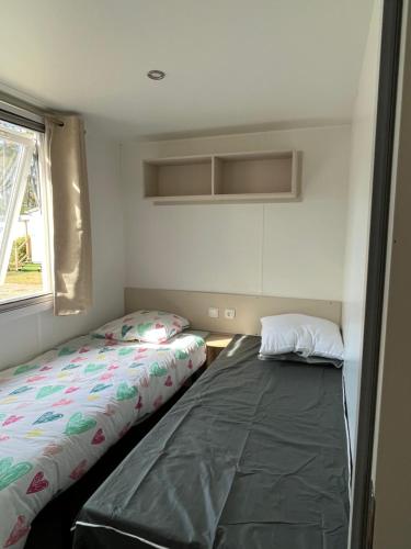 une chambre avec deux lits et une fenêtre dans l'établissement Mobilhome 6 8 pers Les Dunes de Contis, à Saint-Julien-en-Born
