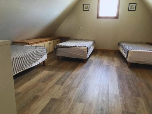 a room with three beds and a wooden floor at Longère - 10 personnes - Vue mer in Tréguennec