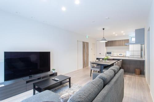 a living room with a couch and a large tv at Mova Villa Haramizu in Kikuchi
