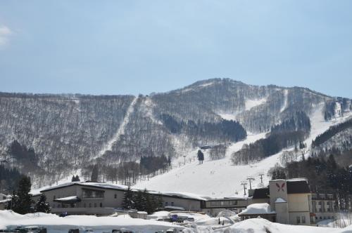 a ski resort with a snow covered mountain in the background at バートンホテル Barton Hotel in Shinano