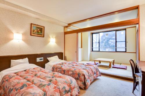 a hotel room with two beds and a window at バートンホテル Barton Hotel in Shinano