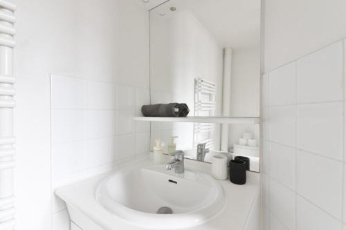 une salle de bain blanche avec un lavabo et un miroir dans l'établissement Studio - Appartement Quartier Champs-Élysées 5 Free Netflix, à Paris