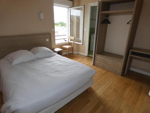 une chambre avec un lit blanc et une grande fenêtre dans l'établissement Grand Hôtel, à Saint-Père-en-Retz