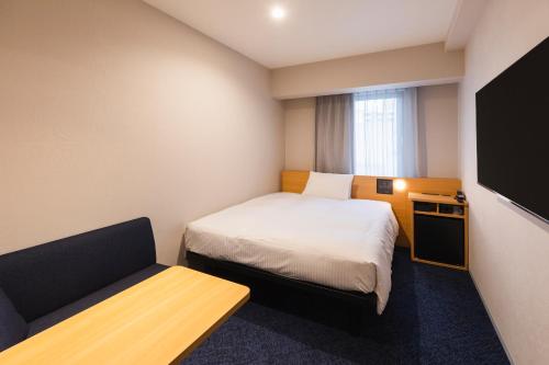 a small room with a bed and a couch at Sotetsu Fresa Inn Sapporo-Susukino in Sapporo