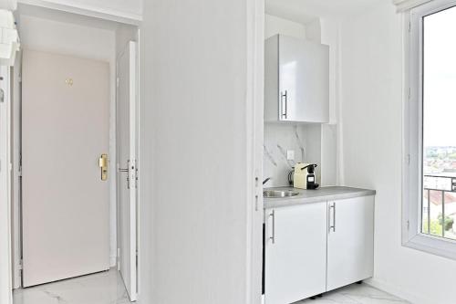 une cuisine avec des armoires blanches, un évier et une fenêtre dans l'établissement Serenity spot at Gagny- Near Paris- III, à Gagny