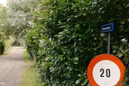 a speed limit sign in front of a bush at Pinecone Hideaway - huis in het bos in Aalter