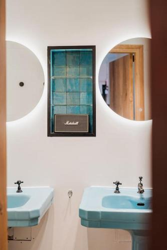 a bathroom with two blue sinks and a mirror at Pinecone Hideaway - huis in het bos in Aalter