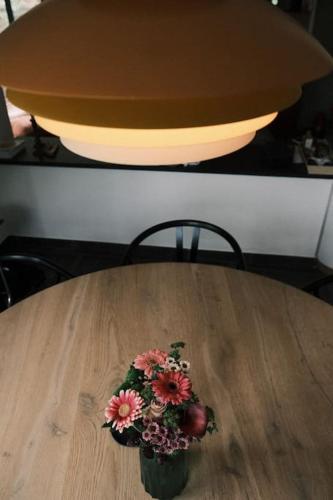 a vase of flowers sitting on a wooden table at Pinecone Hideaway - huis in het bos in Aalter