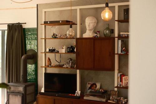 a living room with a tv and a bust on a shelf at Pinecone Hideaway - huis in het bos in Aalter