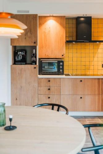 a kitchen with a white table and a microwave at Pinecone Hideaway - huis in het bos in Aalter