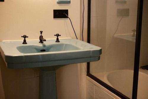 a bathroom sink with two faucets and a shower at Pinecone Hideaway - huis in het bos in Aalter