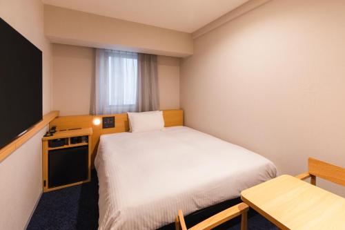 a small room with a bed and a television at Sotetsu Fresa Inn Sapporo-Susukino in Sapporo