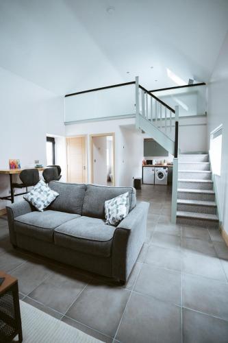a living room with a couch and a staircase at The Byre at Conker Tree Cottages in Saintfield