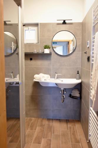 a bathroom with two sinks and two mirrors at PENZION u Restaurace Na Koreji in Štětí