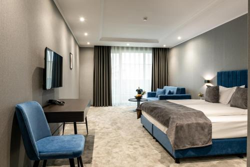 a hotel room with a bed and a desk and chairs at Empire Balneo & Spa Hotel in Hisarya