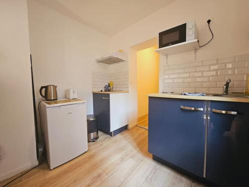 La cuisine est équipée de placards bleus et d'un réfrigérateur blanc. dans l'établissement Charmant Coty pour 4 personnes, Hypercentre, au Havre