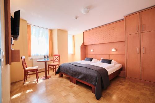 a bedroom with a bed and a table and chairs at JUFA Hotel Meersburg am Bodensee in Meersburg